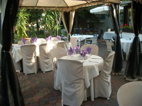 a group of tables with white chairs and purple flowers on them at Hotel Viktória in Balatonalmádi