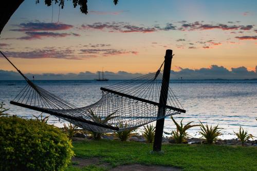 a hammock in front of the ocean at sunset at First Landing Beach Resort & Villas in Lautoka