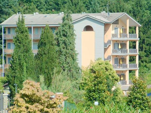 un grand bâtiment avec des arbres devant lui dans l'établissement Apartment in a residence on Lake Maggiore near the beach, à Verbania