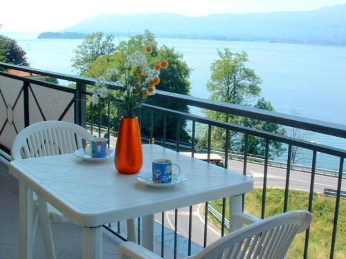 une table blanche avec un vase de fleurs sur un balcon dans l'établissement Apartment in a residence on Lake Maggiore near the beach, à Verbania