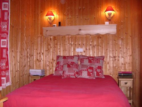 um quarto com uma cama com lençóis vermelhos e 2 candeeiros em Rustic chalet with a dishwasher in the High Vosges em Le Thillot