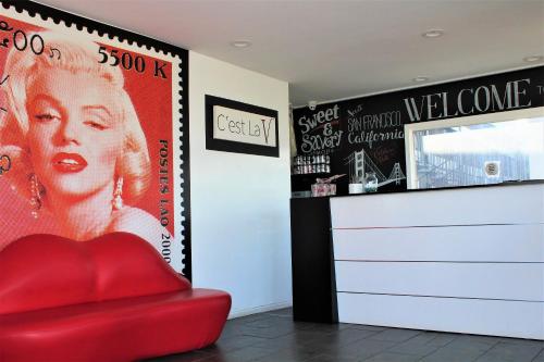 a red chair in a room with a poster of a woman at Rodeway Inn South San Francisco Airport in South San Francisco