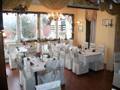 a dining room with white tables and white chairs at Hotel Viktória in Balatonalmádi