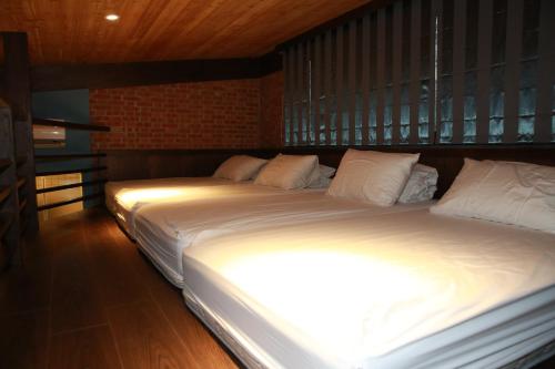 two beds in a room with white sheets and pillows at Old House Homestay in Sanxing