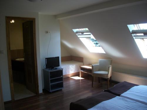 a bedroom with a bed and a desk and a tv at Hotel Viktória in Balatonalmádi