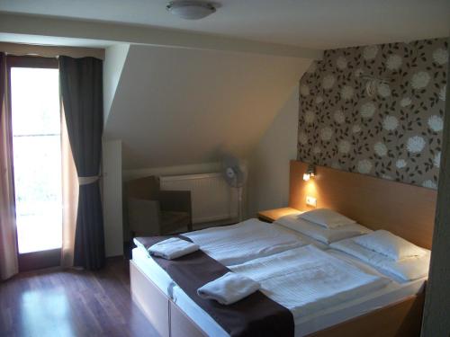 a bedroom with a large bed with towels on it at Hotel Viktória in Balatonalmádi