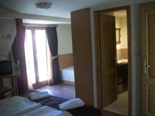 a bedroom with a bed and a bathroom with a mirror at Hotel Viktória in Balatonalmádi