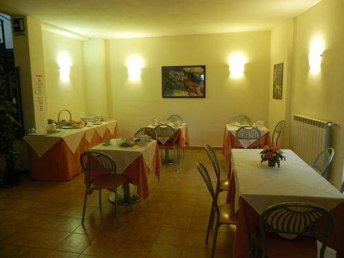 een restaurant met verschillende tafels en stoelen met witte en oranje tafels bij Hotel Il Saraceno in Volastra