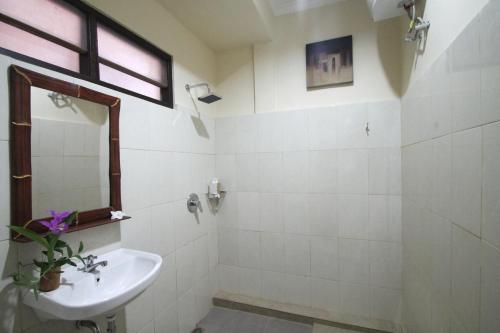 a white bathroom with a sink and a mirror at Pondok Muwa Guest House in Ubud