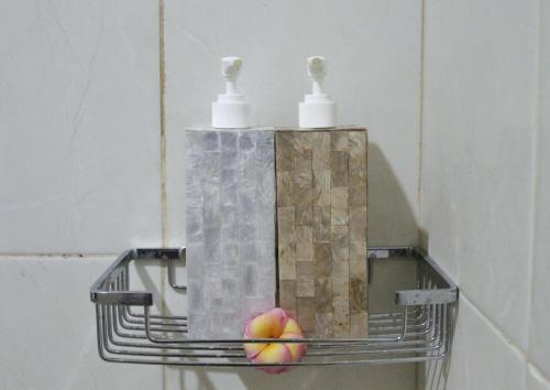 a metal shelf with two apples and two soap dispensers at Pondok Muwa Guest House in Ubud