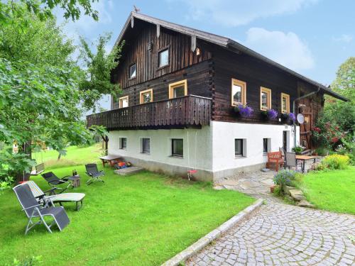 una grande casa in legno con sedie nel cortile di Holiday home with terrace a Weigelsberg