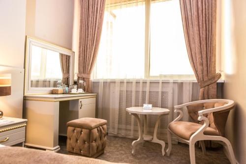 a bedroom with a chair and a table and a window at Grand Sapphire Hotel in Almaty