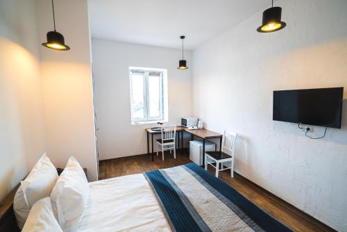 a bedroom with a bed and a desk and a television at Citadel Express in Tbilisi City