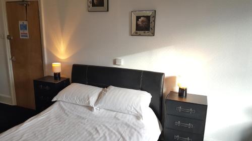 a bedroom with a bed with white sheets and two night stands at Station Hotel in Hucknall