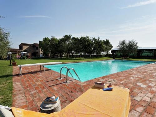 Una donna seduta su una coperta accanto alla piscina di Scenic Home in Foiano della Chiana with Terrace a Foiano della Chiana