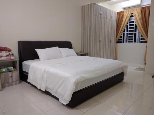 a bedroom with a large bed with white sheets at Homestay Mama D'Chandan in Kuala Kangsar
