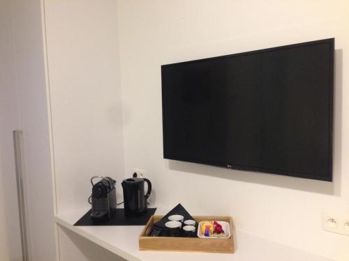TV de pantalla plana colgada en la pared en Comfort Aan Zee Guestrooms en Ostende