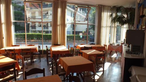 a restaurant with tables and chairs in a room with windows at Hotel Colibrì in Finale Ligure