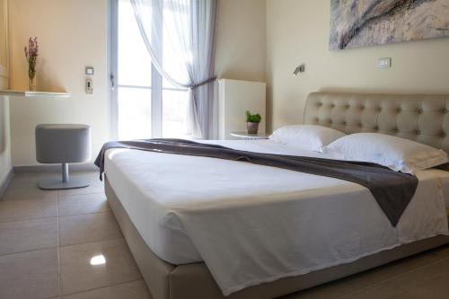 um quarto com uma cama grande com lençóis brancos e uma janela em Villa Lefteris em Svoronata