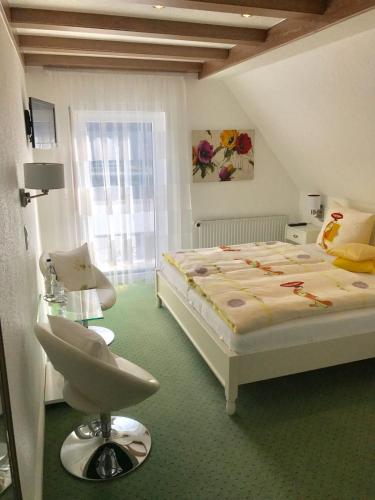 a bedroom with a bed and a chair and a window at Haus Marientaler Au GbR in Zell an der Mosel