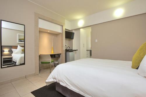 a bedroom with a large white bed with a mirror at The Park Lodge Hotel in Pretoria