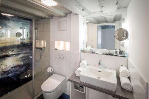 a white bathroom with a toilet and a sink at Hotel Alte Schule in Lindau