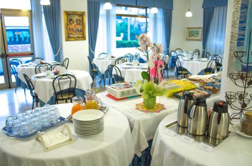 een eetkamer met tafels met witte tafelkleden bij Hotel Paradise in Fano