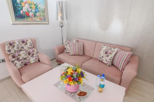 een woonkamer met een bank en een tafel met bloemen bij Phoenicia Luxury Hotel in Mamaia Nord – Năvodari