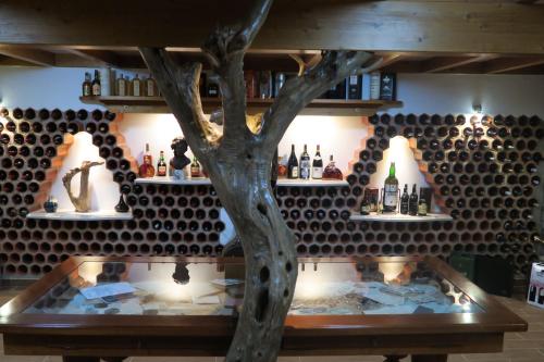 a table with a tree in front of a wall of wine bottles at Noz Por Cá... Turismo Em Espaco Rural in Alcaria