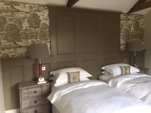 1 dormitorio con 2 camas y una pared con una pintura en Hill Farm Bed and Breakfast, en Little Massingham