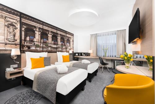 ブダペストにあるメルキュール ブダペスト シティ センターのベッド2台とデスクが備わるホテルルームです。