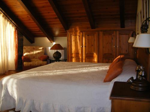 a bedroom with a large white bed with wooden ceilings at Hotel Palazio in Nerín