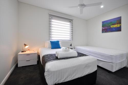 a white bedroom with two beds and a window at Coastal By Rockingham Apartments in Rockingham