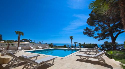 a swimming pool with chaise lounge chairs next to a resort at Hotel Kvarner - Liburnia in Opatija