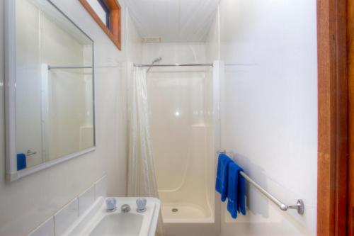 a white bathroom with a shower and a sink at Twin Dolphins Holiday Park in Tuncurry