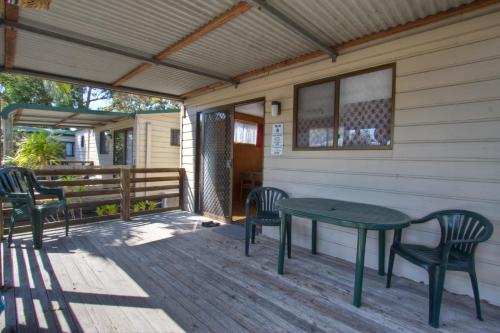 a porch with a table and chairs on it at Twin Dolphins Holiday Park in Tuncurry