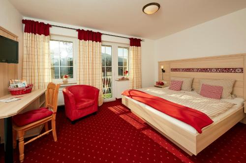 a bedroom with a bed and a desk and a chair at Hotel Garni Dorfkammer in Olsberg