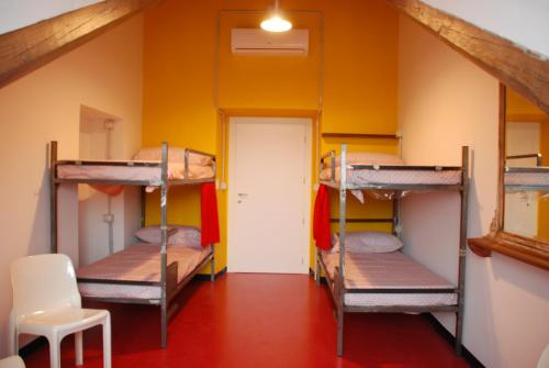 a room with three bunk beds and a chair at Attic Hostel Torino in Turin