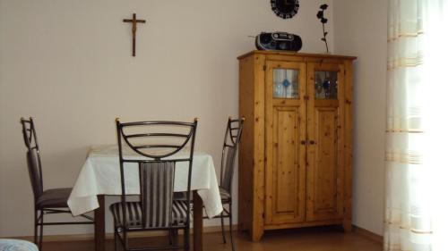 a dining room with a table and a cross on the wall at Appartementhaus Scholz in Egglfing