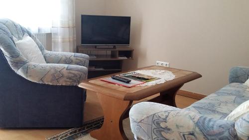 un soggiorno con 2 sedie, un tavolo e una TV di Appartementhaus Scholz a Egglfing