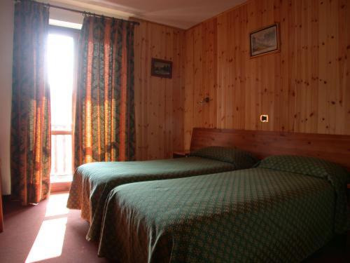 sypialnia z 2 zielonymi łóżkami i oknem w obiekcie Park Hotel Gran Bosco w mieście Sauze dʼOulx