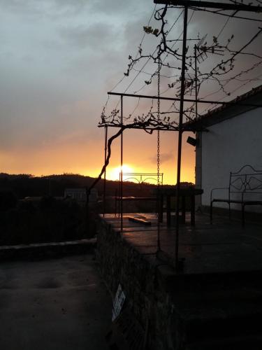 a sunset behind a fence with the sun setting in the background at Albergue Casa do Sardão in Carreço