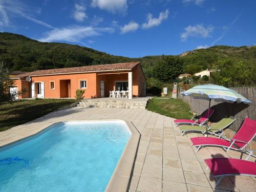 a pool with chairs and an umbrella and a house at Luxurious Villa in Thueyts with Private Pool in Thueyts