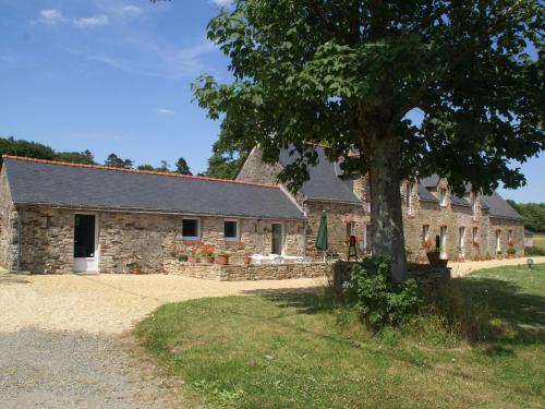 a stone barn with a tree in front of it at Spacious Holiday Home in Ass rac with a Fenced Pond in Assérac