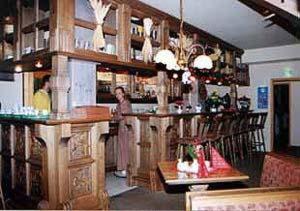 a woman standing at a bar in a restaurant at Landhotel Osterlamm in Grünhain