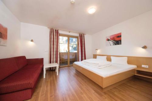 a bedroom with a bed and a red couch at Haus Renate in Kaunertal
