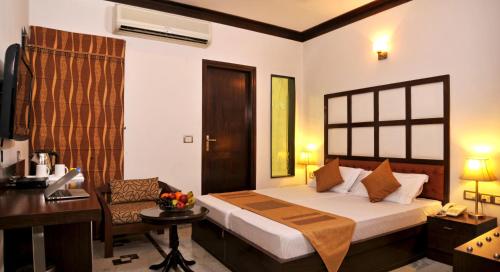 a bedroom with a bed and a desk and a chair at Hotel Citi International in New Delhi