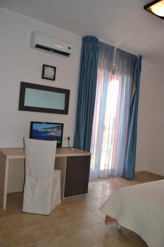 a bedroom with a desk and a window with blue curtains at Hotel La Siesta in Torino di Sangro