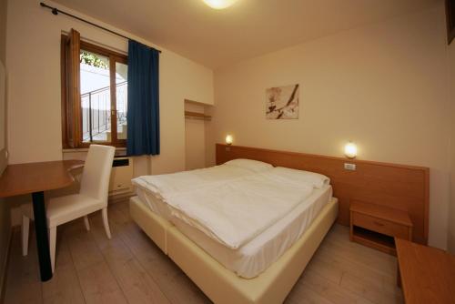a bedroom with a bed and a desk and a window at Casa Vacanze Sole in Tremosine Sul Garda