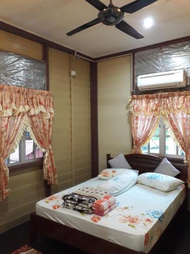 um quarto com uma cama, uma ventoinha de tecto e janelas em Teratak Opah Kamunting em Taiping